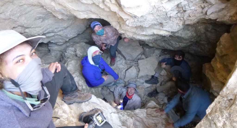 a group of gap year students smile while looking up from a rocky canyon